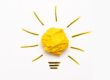 A yellow paper lightbulb thats centered on a off white background representing the ideas of how to find donor eggs.