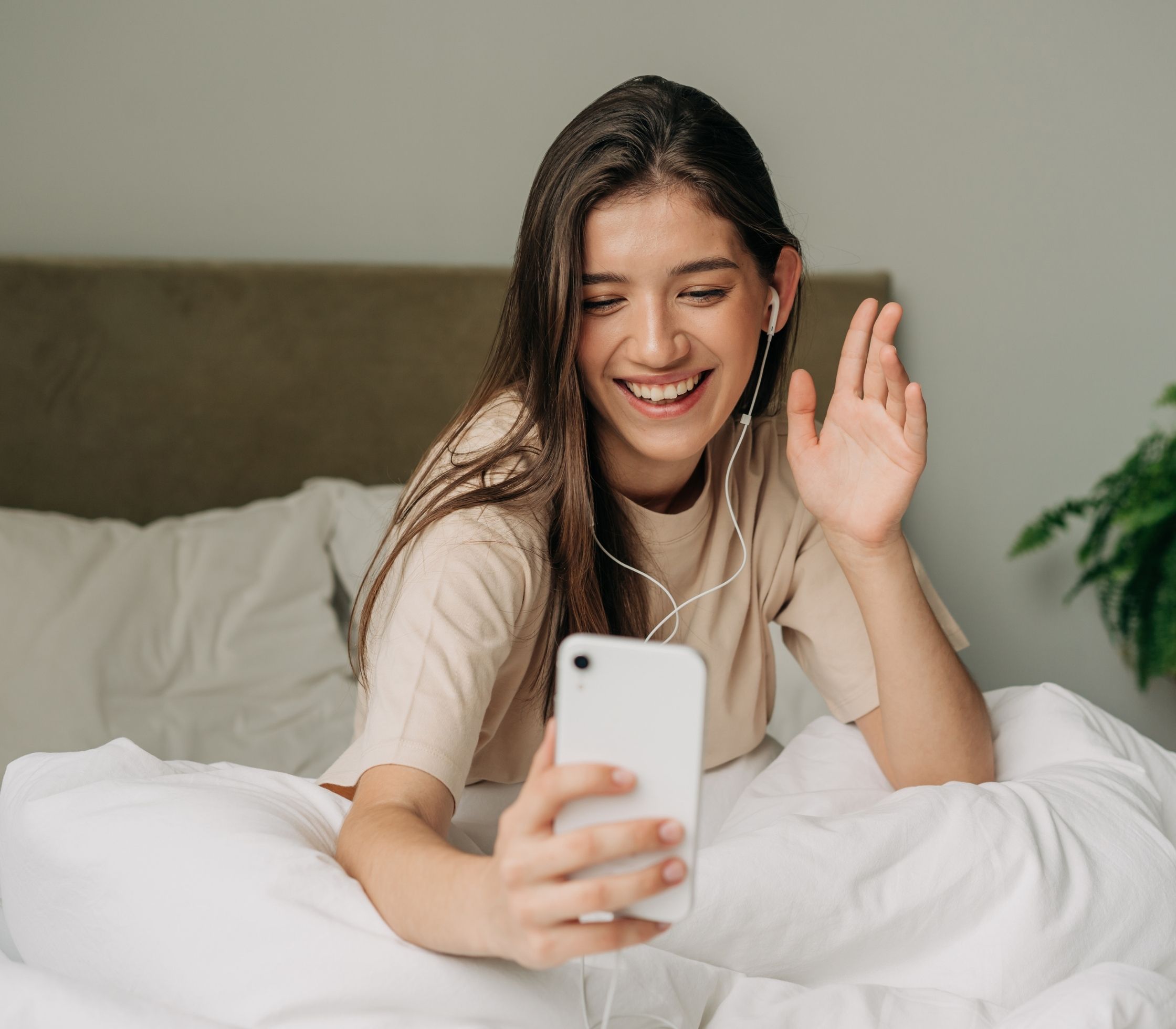 A women in bed smiling as she talks to someone on her phone representing why can you only donate eggs six times.